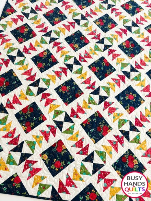 A colorful patchwork quilted blanket with floral and geometric blocks in navy, red, orange, yellow, and green autumn colors. Gift ideas men and women for birthdays, Christmas, Housewarming, and Wedding Gifts for Brides and Grooms.