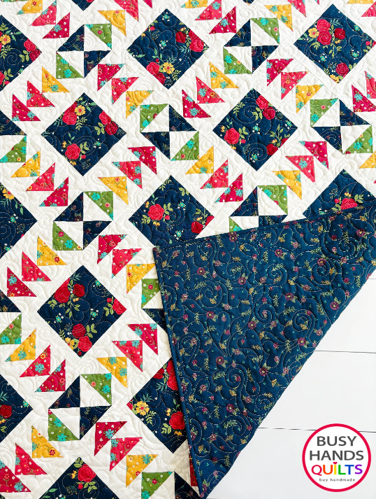 A colorful patchwork quilted blanket with floral and geometric blocks in navy, red, orange, yellow, and green autumn colors. Gift ideas men and women for birthdays, Christmas, Housewarming, and Wedding Gifts for Brides and Grooms.