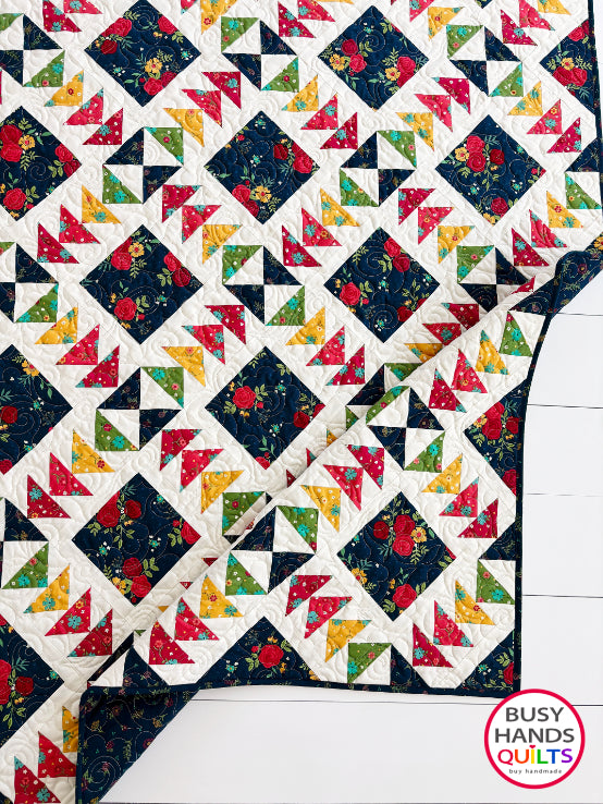 A colorful patchwork quilted blanket with floral and geometric blocks in navy, red, orange, yellow, and green autumn colors. Gift ideas men and women for birthdays, Christmas, Housewarming, and Wedding Gifts for Brides and Grooms.
