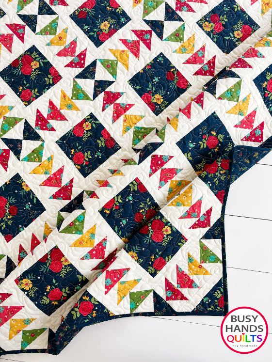 A colorful patchwork quilted blanket with floral and geometric blocks in navy, red, orange, yellow, and green autumn colors. Gift ideas men and women for birthdays, Christmas, Housewarming, and Wedding Gifts for Brides and Grooms.