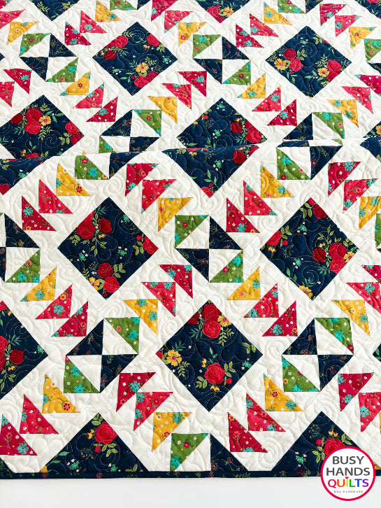 A colorful patchwork quilted blanket with floral and geometric blocks in navy, red, orange, yellow, and green autumn colors. Gift ideas men and women for birthdays, Christmas, Housewarming, and Wedding Gifts for Brides and Grooms.