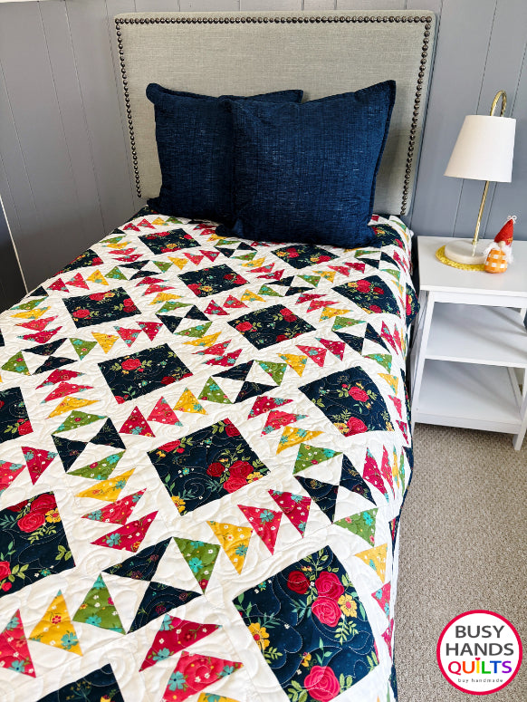 A colorful patchwork quilted blanket with floral and geometric blocks in navy, red, orange, yellow, and green autumn colors. Gift ideas men and women for birthdays, Christmas, Housewarming, and Wedding Gifts for Brides and Grooms.
