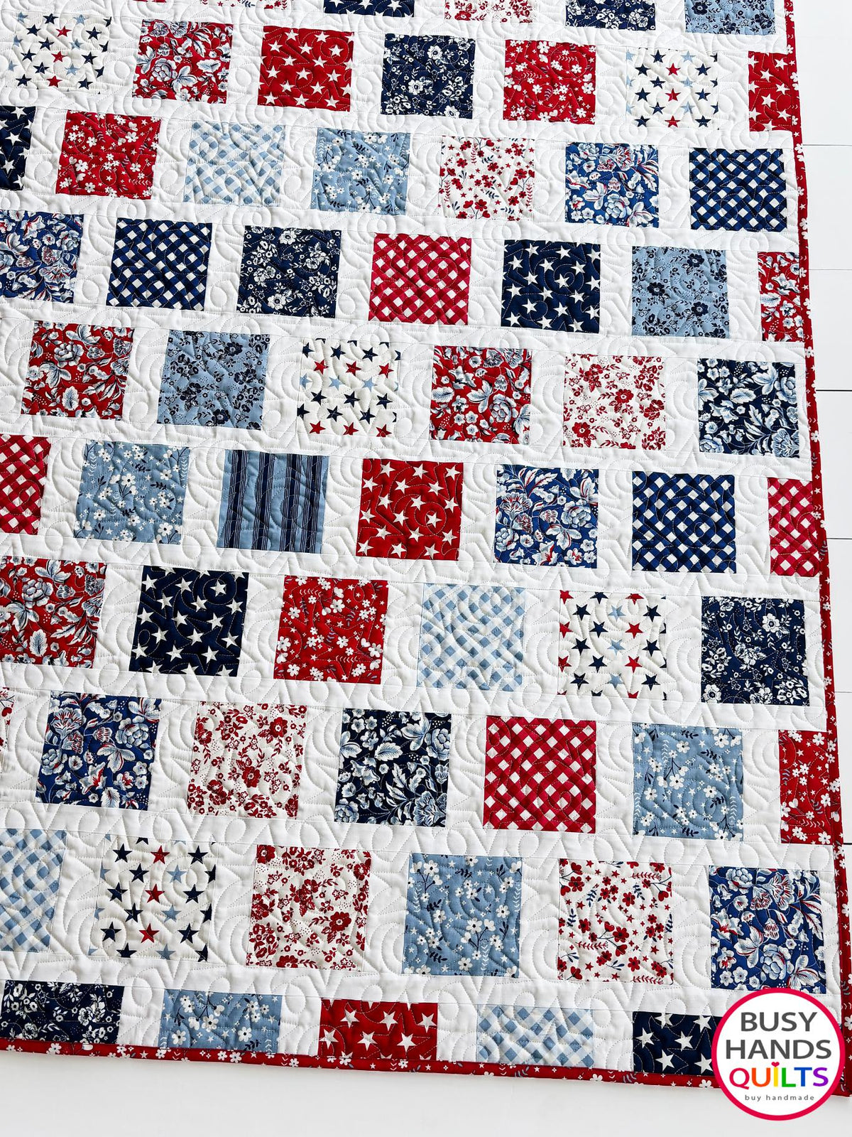 A patriotic-themed patchwork quilted bedspread with red, white, and blue squares. Americana throw sofa blanket, decor for 4th of July stars and summer. Gift ideas for birthdays, Christmas, housewarming, and wedding gifs for brides and grooms.