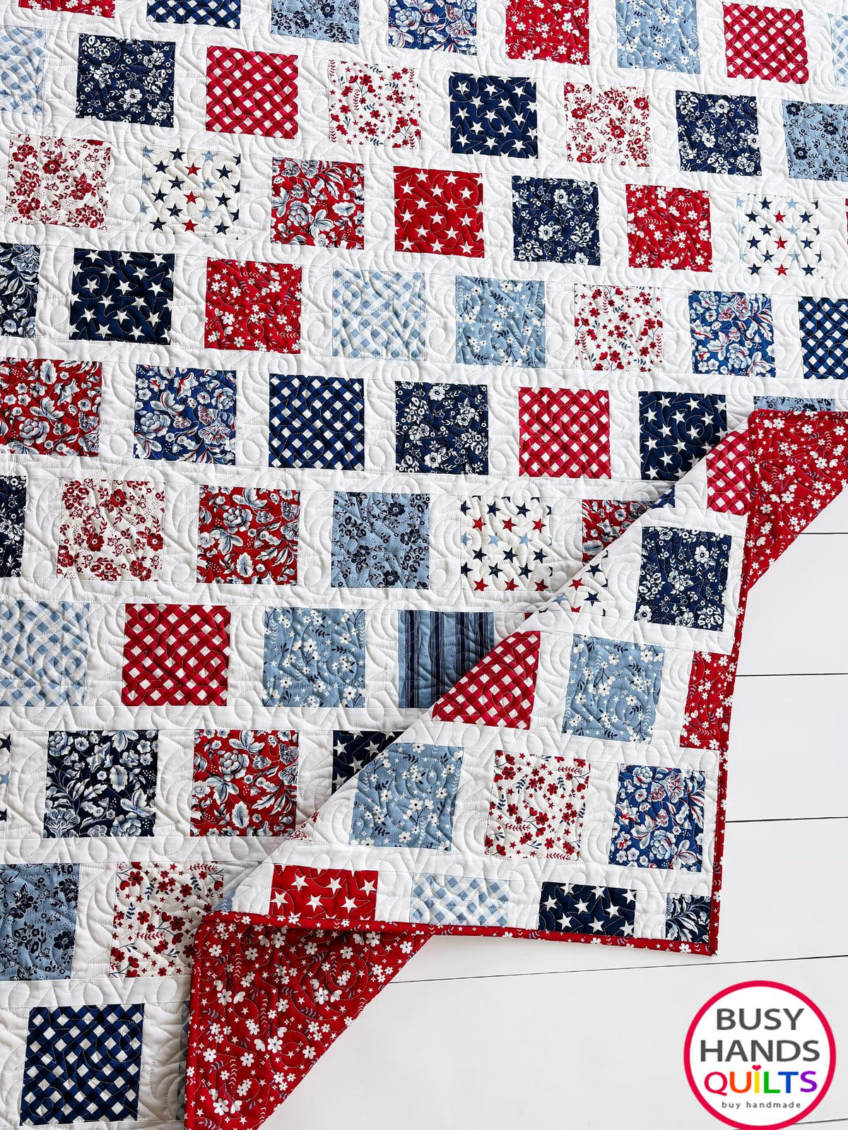 A patriotic-themed patchwork quilted bedspread with red, white, and blue squares. Americana throw sofa blanket, decor for 4th of July stars and summer. Gift ideas for birthdays, Christmas, housewarming, and wedding gifs for brides and grooms.