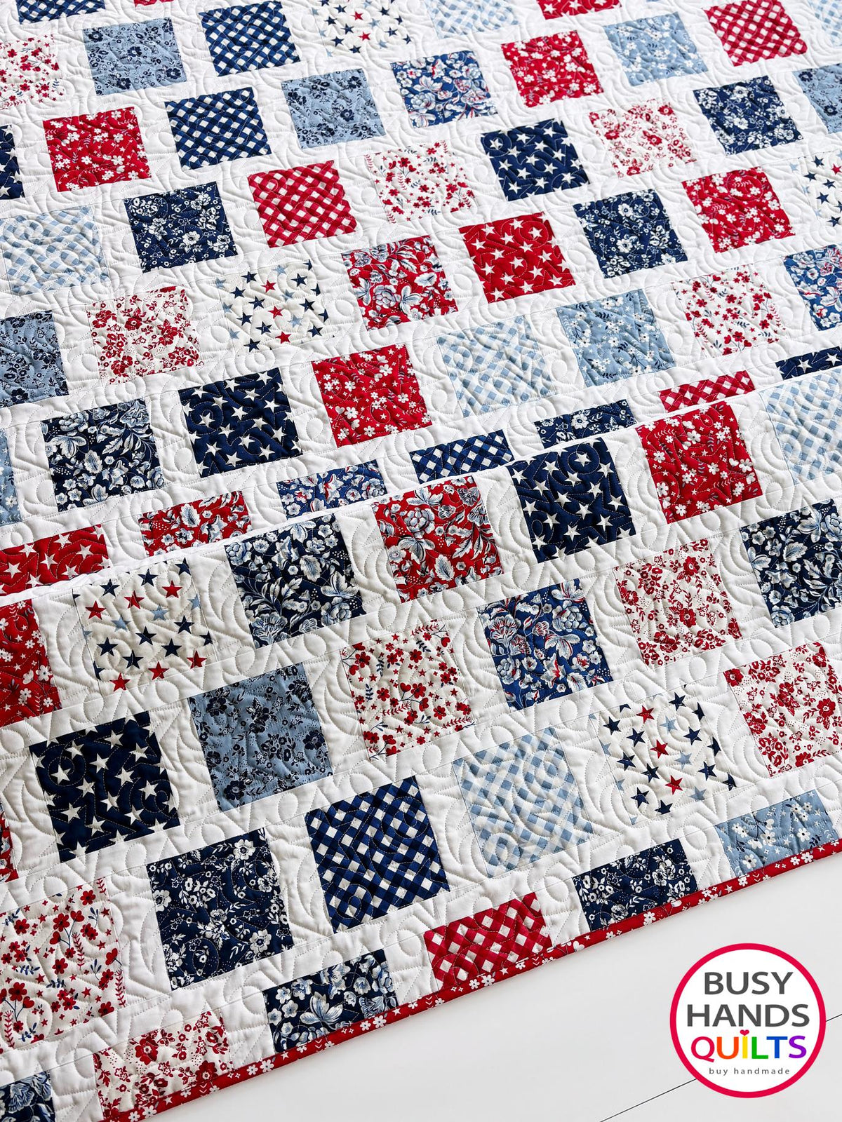 A patriotic-themed patchwork quilted bedspread with red, white, and blue squares. Americana throw sofa blanket, decor for 4th of July stars and summer. Gift ideas for birthdays, Christmas, housewarming, and wedding gifs for brides and grooms.